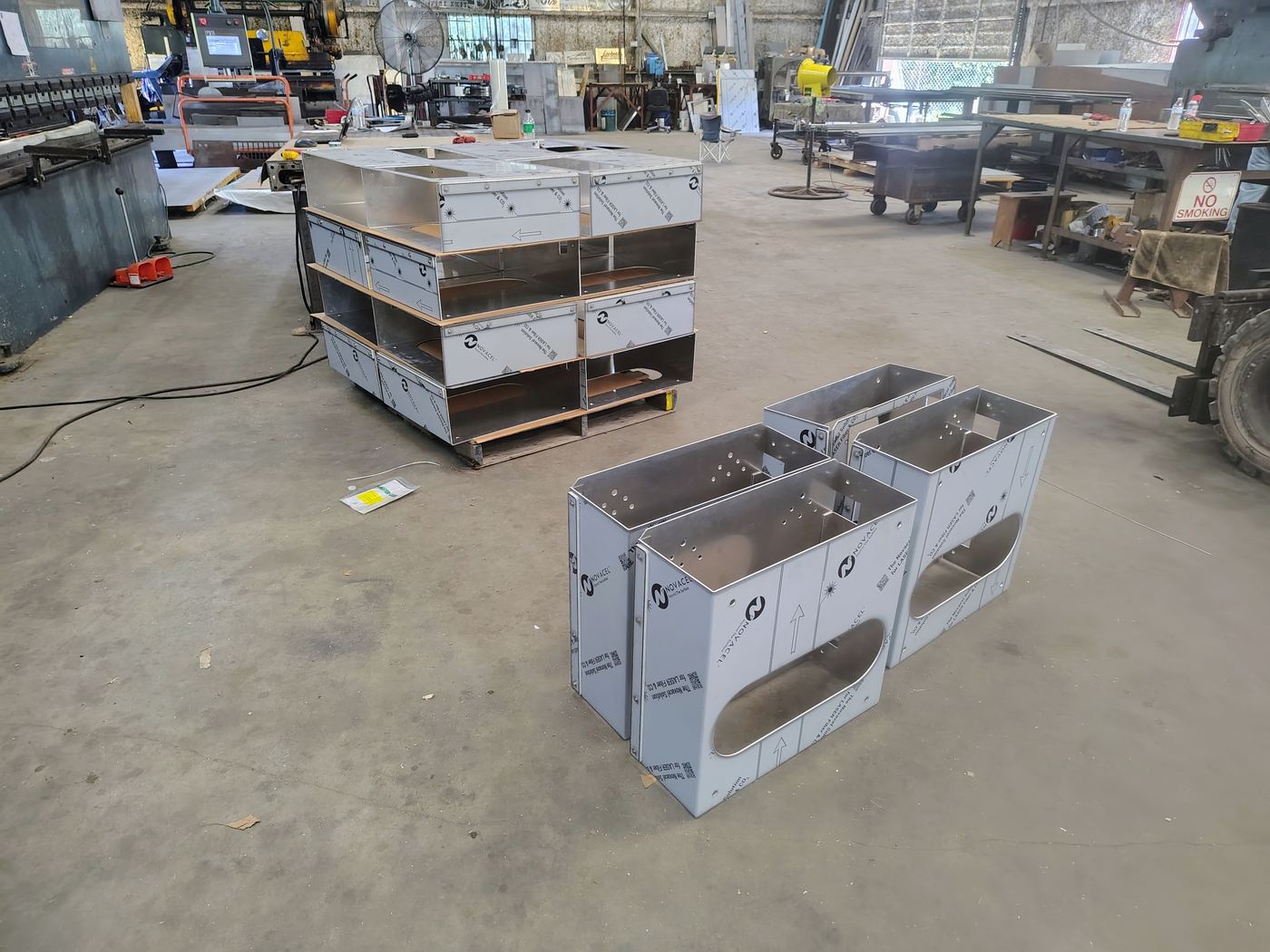 Finished aluminum enclosures stacked on a pallet with more completed units on the shop floor