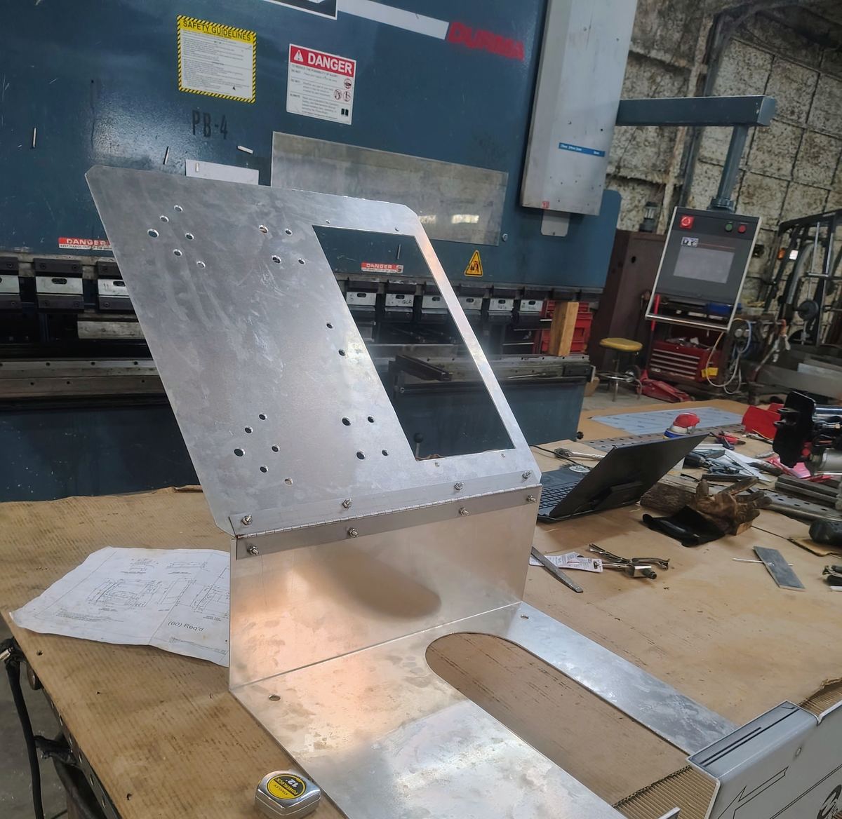 Finished formed aluminum enclosure panel in front of the press brake